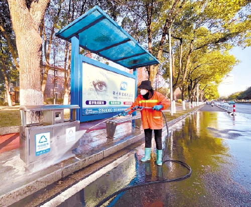环卫工人在滨湖西路清洗公交站台公共座椅和垃圾桶